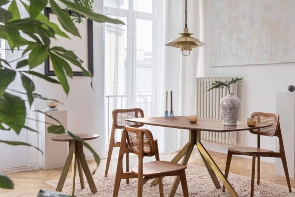 Stylish and modern dining room interior with design sharing table, chairs, gold pendant lamp, abstract paintings, plants and elegant accessories. Tropical leafs in vase. Eclectic home decor. ; Shutterstock ID 1377513215; purchase_order: -; job: -; client: -; other: -